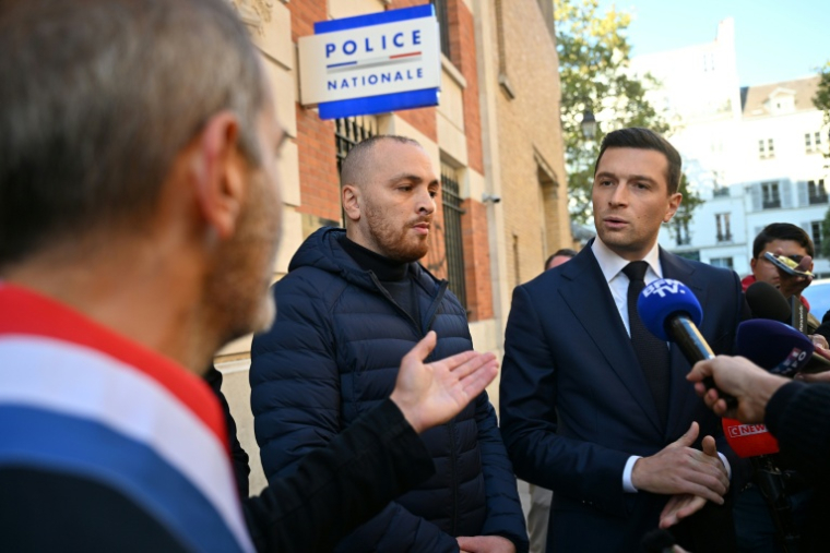 Le président du RN Jordan Bardella (d) s'adresse à la presse après avoir visité le commissariat du 3e arrondement de Paris, le 18 octobre 2026 ( AFP / Matthieu RONDEL )