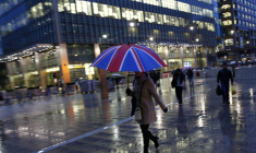 Des travailleurs marchent sous la pluie dans le quartier d'affaires de Canary Wharf à Londres