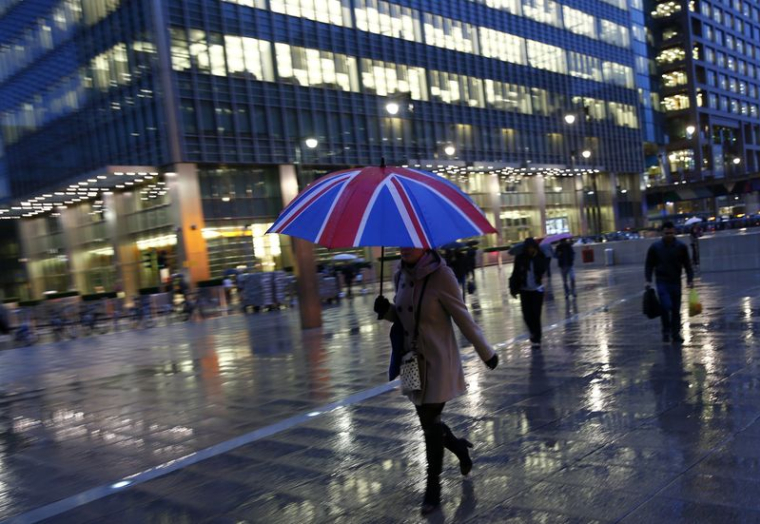 Des travailleurs marchent sous la pluie dans le quartier d'affaires de Canary Wharf à Londres