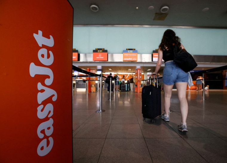 Un passager passe devant un logo easyJet dans la zone d'enregistrement, lors d'une grève du personnel de cabine, à Barcelone