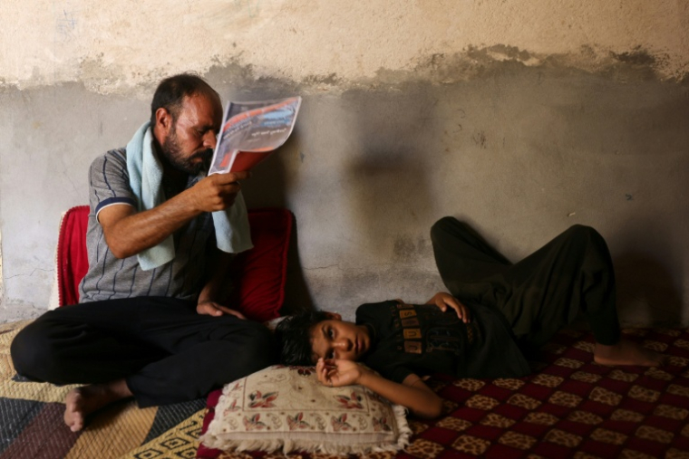 Un homme tente de rafraîchir son fils, à Hilla, dans le centre de l'Irak, le 10 août 2025 ( AFP / AHMAD AL-RUBAYE )