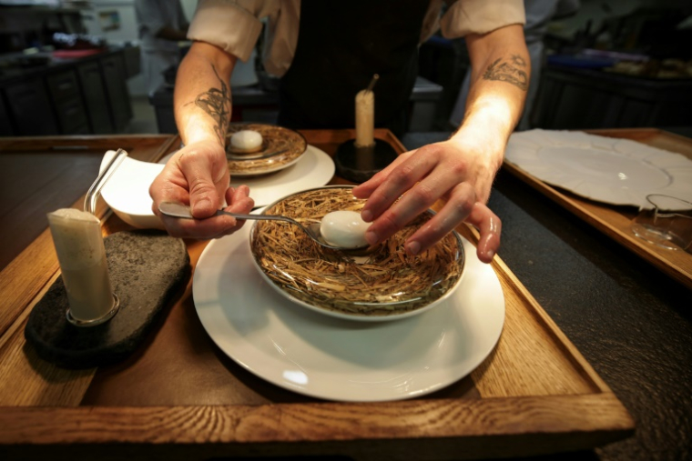 Un sous-chef prépare un plat emblématique du chef étoilé Gilles Goujon, l'œuf de poule "Carrus" pourri à la truffe, au restaurant "Auberge du Vieux Puits" à Fontjoncouse (Aude), le 25 avril 2025 ( AFP / Valentine CHAPUIS )