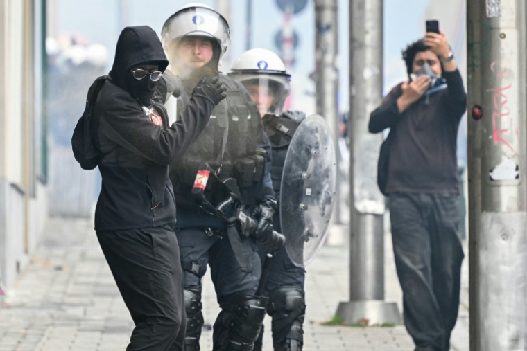 Un policier belge utilise une bombe de gaz sur un manifestant durant une manifestation syndicale à Bruxelles le 9 octobre 2026 ( AFP / NICOLAS TUCAT )