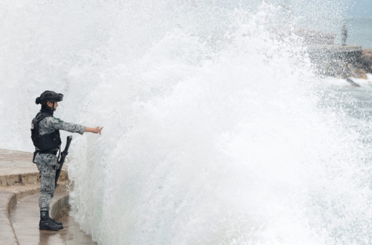 Un membre de la Garde nationale mexicaine se tient sur la promenade de Puerto Vallarta tandis que les vagues s'écrasent contre le littoral, dans l'État de Jalisco, au Mexique, le 11 octobre 2026 ( AFP / ULISES RUIZ )