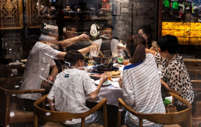 Des convives partagent un repas autour d'une table de « hot pot » chinois dans un restaurant traditionnel de Pékin