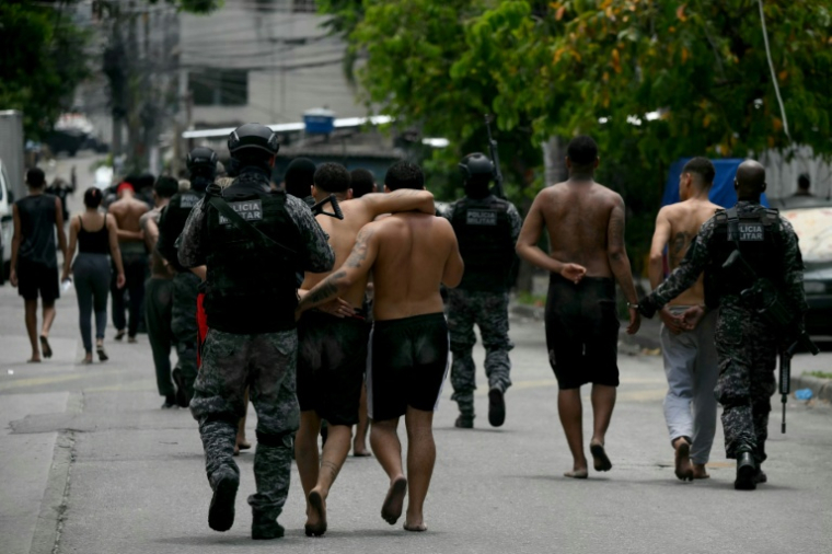 Des policiers escortent des criminels présumés arrêtés lors d'une opération dans la favela de Vila Cruzeiro, dans le complexe de Penha, à Rio de Janeiro, le 28 octobre 2025 au Brésil ( AFP / Mauro PIMENTEL )