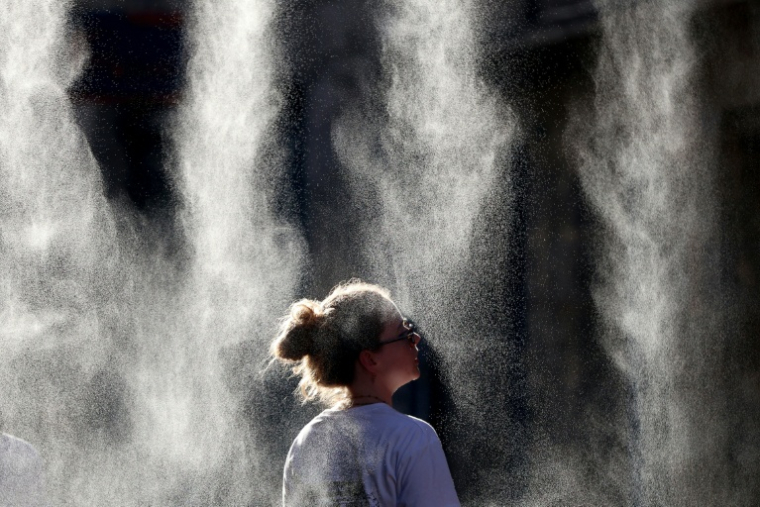 Une femme se rafraîchit sous un brumisateur à Bordeaux, le 21 juin 2026 ( AFP / ROMAIN PERROCHEAU )