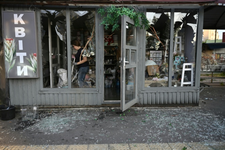 Une employée nettoie une boutique de fleur, dont le sol est recouvert de débris, à la suite d'une frappe de missile russe le 1er août 2026 à Kiev ( AFP / Genya Savilov )