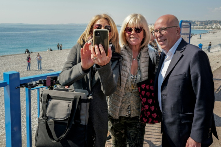 Le nouveau maire de Nice UDR Eric Ciotti, à droite, pose pour une photo avec des passantes sur la Promenade des Anglais à Nice le 23 mars 2026 ( AFP / Valery HACHE )