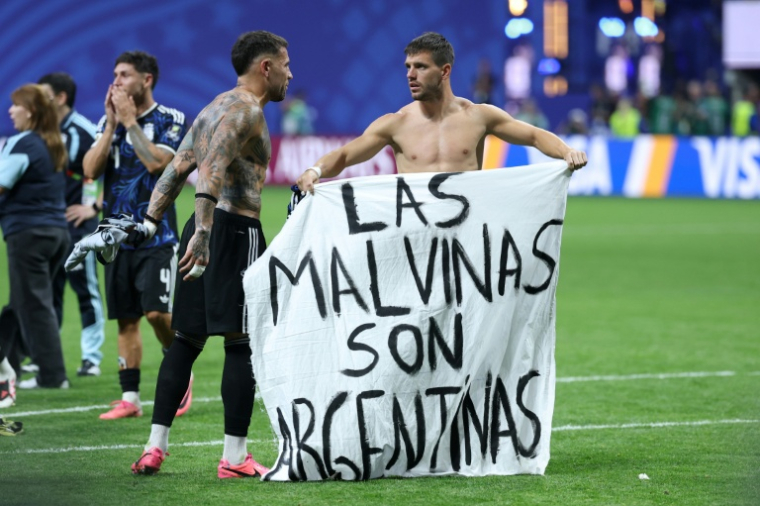 Le milieu de terrain argentin Giovani Lo Celso (à droite) et le défenseur Nicolas Otamendi déploient une banderole proclamant: "Les Malouines sont argentines", à l'issue de la demi-finale du Mondial 2026 contre l'Angleterre, le 15 juillet 2026 à Atlanta ( AFP / Thomas COEX )
