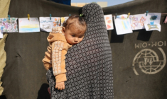 Une femme portant un enfant dans une école transformée en abri pour les Palestiniens déplacés dans le quartier d'Al-Rimal de la ville de Gaza, le 5 novembre 2025 ( AFP / Omar AL-QATTAA )