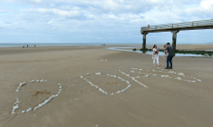 Une famille sur "Omaha Beach", où le mot "D-Day" a été tracé à l'aide de galets, à  Vierville-sur-Mer, dans le Calvados, lors des célébrations du 75e anniversaire du Débarquement en juin 2019 ( AFP / JEAN-FRANCOIS MONIER )