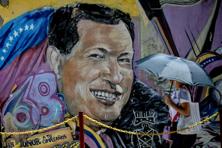 Une femme se protégeant du soleil avec un parapluie arrive au mausolée de l'ancien président vénézuélien Hugo Chavez à Caracas, le 5 mars 2026 ( AFP / Juan BARRETO )