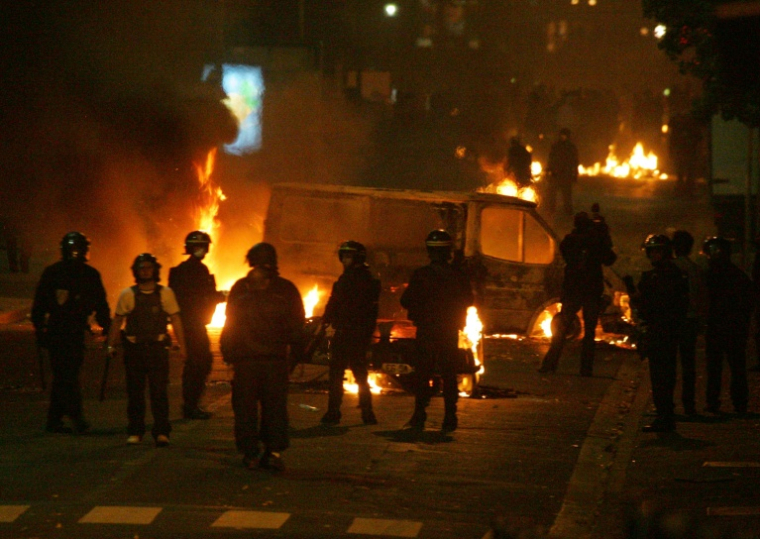 Des policiers devant des véhicules incendiés, le 28 octobre 2005 à Clichy-sous-Bois, en Seine-Saint-Denis, où de nouvelles violences urbaines ont éclaté entre des jeunes des quartiers difficiles et les forces de l'ordre ( AFP / Joël SAGET )