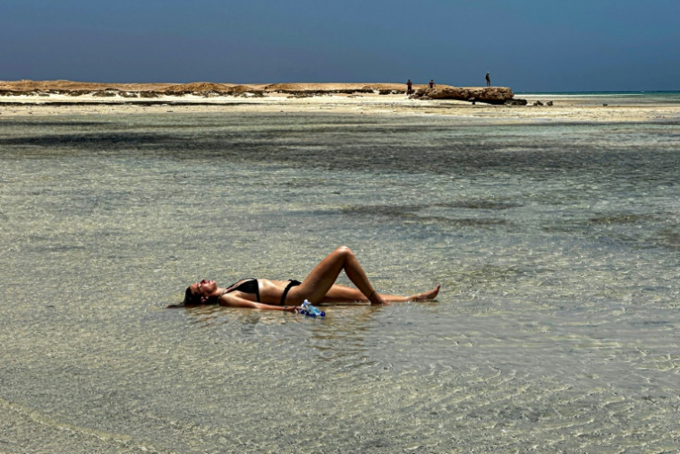 Une touriste est allongée dans les eaux de la plage de Ras Hankorab, dans la réserve naturelle de Wadi Al-Gemal, sur la mer Rouge, dans le sud-est de l'Egypte, le 28 mai 2025 ( AFP / Khaled DESOUKI )