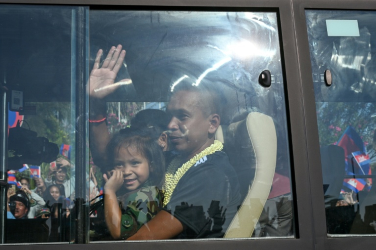 Un soldat cambodgien, capturé par la Thaïlande en juillet, salue la foule depuis un bus après sa libération, alors que le groupe quitte l'ancien aéroport international de Phnom Penh le 31 décembre 2025 ( AFP / TANG CHHIN Sothy )