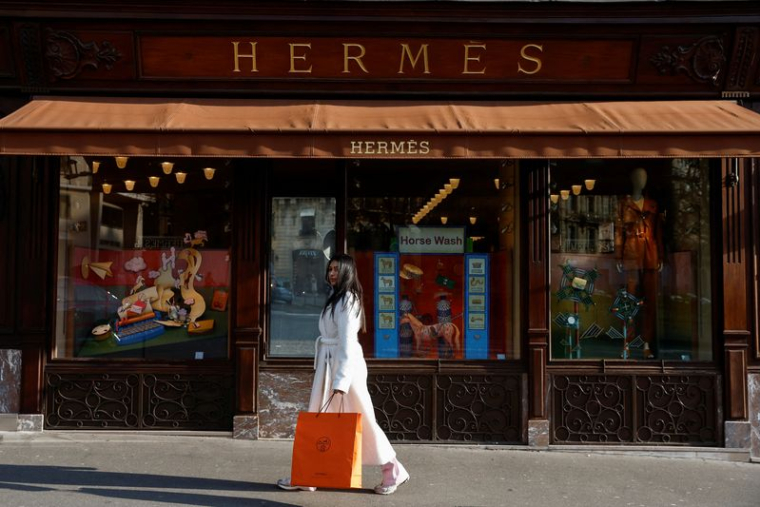 Une femme marche devant un magasin Hermès à Paris