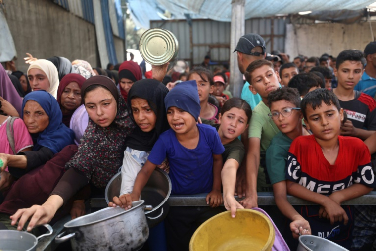 Des enfants palestiniens se rassemblent pour recevoir des portions alimentaires distribuées par une cuisine caritative à Nousseirat, dans le centre de la bande de Gaza, le 30 septembre 2025 ( AFP / Eyad BABA )