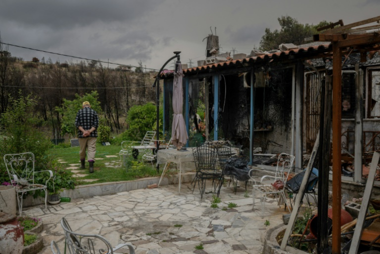Un habitant à côté de sa maison endommagée par les incendies de forêt de l'été dernier, à Penteli, dans la banlieue d'Athènes, le 16 mai 2025 en Grèce ( AFP / Angelos TZORTZINIS )