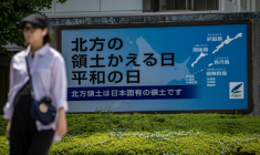 A woman walks past a Japanese government sign reading "Day of the Return of the Northern Territories, Day of Peace. The Northern Territories are an inherent part of Japan's territory,"　referring to the Russian-controlled Southern Kuril Islands claimed by Japan as its Northern Territories, in Tokyo on August 19, 2026. Bilateral relations have long been strained over the Kurils, known in Japan as the Northern Territories. After Russia's President Vladimir Putin visited the islands on August 13, Japan summoned the Russian ambassador in protest, and Russia followed suit. ( AFP / Yuichi YAMAZAKI )