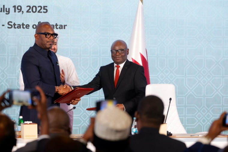 Le chef de la délégation congolaise Sumbu Sita Mambu (G) serre la main du secrétaire exécutif du groupe armé M23,  Benjamin Mbonimpa (D), après avoir signé une déclaration de principe comprenant un accord de cessez-le-feu, le 19 juillet 2025 à Doha ( AFP / Karim JAAFAR )