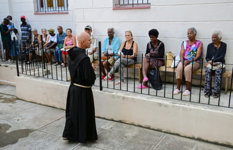 Le frère franciscain Luis Pernas s'adresse à des habitants qui patientent devant l'église catholique Santa Cruz de Jérusalem avant une distribution gratuite de médicaments, à La Havane, le 14 avril 2026 ( AFP / YAMIL LAGE )