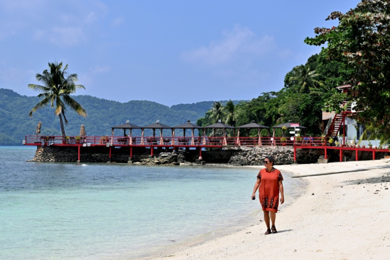 La sociologue paluane Madelsar Ngiraingas marchant sur une plage à Koror, aux Palaos où les projets de l’armée américaine visant à reconstruire le port principal de cet archipel immaculé du Pacifique ravivent de douloureux souvenirs de la Seconde Guerre mondiale, le 5 septembre 2026 ( AFP / Saeed KHAN )