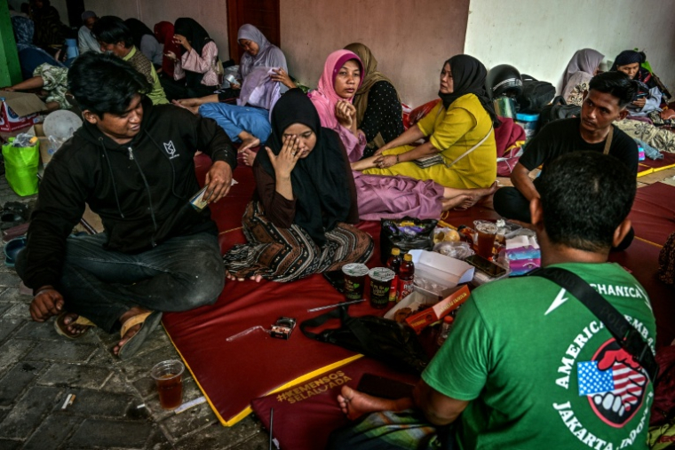 Des proches d'élèves disparus attendent des nouvelles pendant les recherche de victimes à l'école islamique Al Khoziny à Sidoarjo, dans la province de Java oriental, après l'effondrement d'un bâtiment pendant les prières, le 5 octobre 2025 en Indonésie ( AFP / JUNI KRISWANTO )