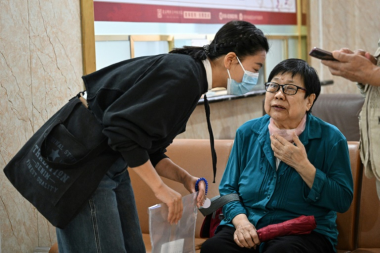 Meng Jia (g), une accompagnatrice de patient, assiste Gao Yingmin (d) pour la guider dans un hôpital à Pékin, le 22 mai 2025 en Chine ( AFP / Jade GAO )