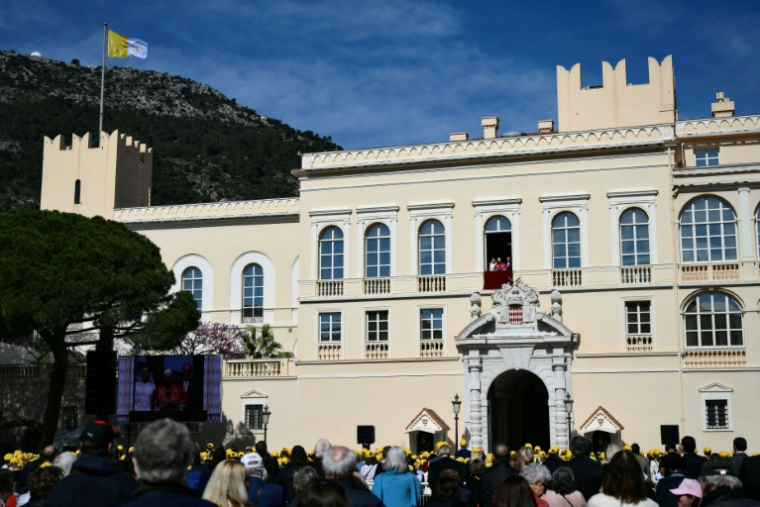 Des fidèles dans la cour du palais princier de Monaco écoutent le pape Léon XIV qui s'exprime depuis le balcon, le 28 mars 2026  ( AFP / Marco BERTORELLO )