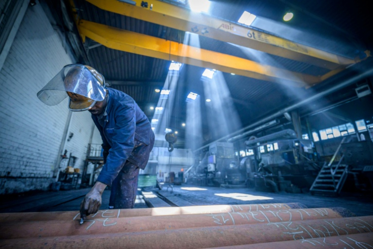 Un ouvrier appose des étiquettes sur des barres en alliage de cuivre fraîchement coulées à l'usine de tubes MPG (Mendener Präzisionsrohr GmbH) de Menden, dans l'ouest de l'Allemagne, le 18 juin 2026 ( AFP / SASCHA SCHUERMANN )