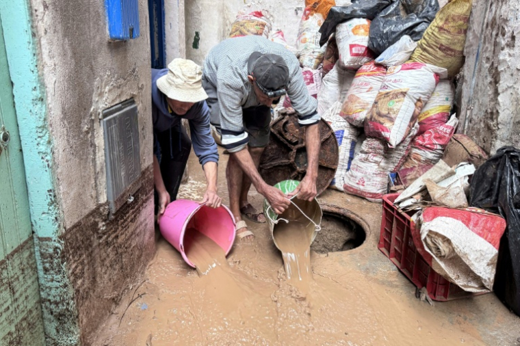 Des Marocains utilisent des seaux pour évacuer l'eau et la boue accumulées dans la cour d'une maison après une crue soudaine, dans la ville côtière de Safi, à environ 300 kilomètres au sud de la capitale Rabat, le 15 décembre 2025 ( AFP / - )