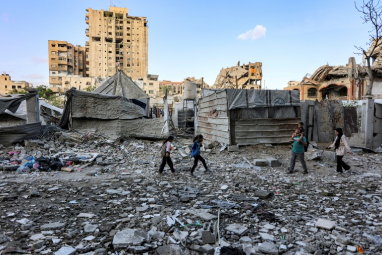 Des habitants passent devant un immeuble résidentiel touché la veille par une frappe israélienne dans le quartier d'Al-Ramal à Gaza, le 16 mai 2026 ( AFP / Omar AL-QATTAA )