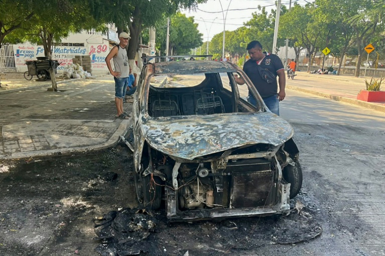 Des personnes inspectent une voiture incendiée à la suite d'une opération de l'armée colombienne contre le groupe armé ACSN, à Santa Marta, en Colombie, le 22 septembre 2026 ( AFP / Idinael FERNANDEZ )
