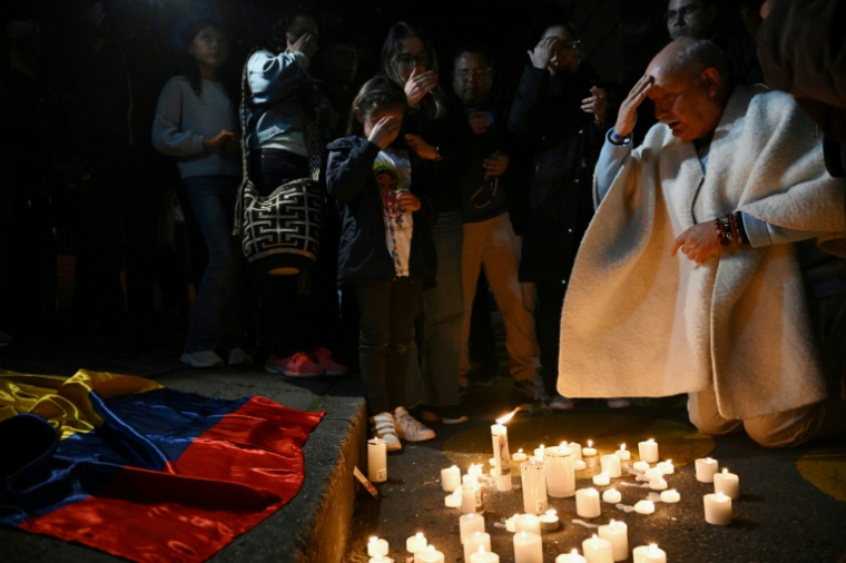 Des personnes prient après avoir allumé des bougies devant la clinique Sante Fe où le sénateur conservateur Miguel Uribe reçoit des soins médicaux après avoir été blessé par balle lors d'un meeting à Bogota, le 7 juin 2025 ( AFP / Raul ARBOLEDA )