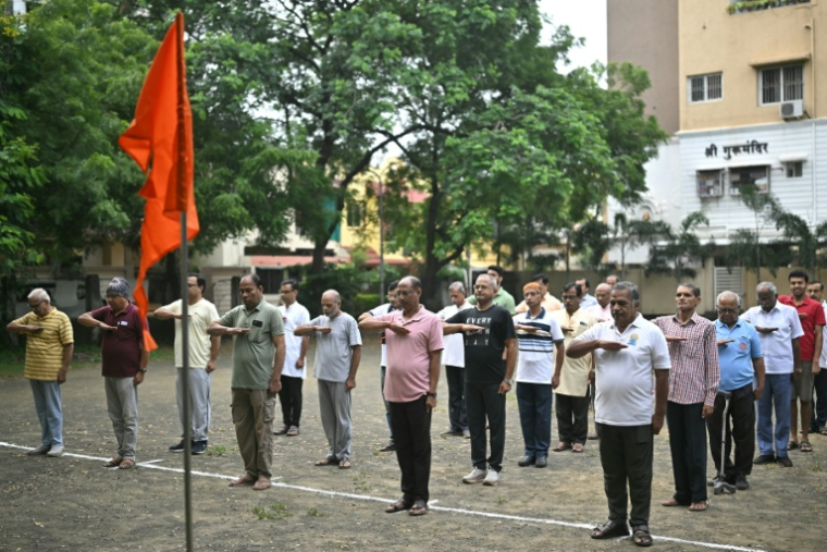 Des membres du "RSS" saluent le drapeau orange de l'organisation avant des exercices matinaux, dans un parc de Nagpur, le 3 octobre 2025 ( AFP / Idrees MOHAMMED )