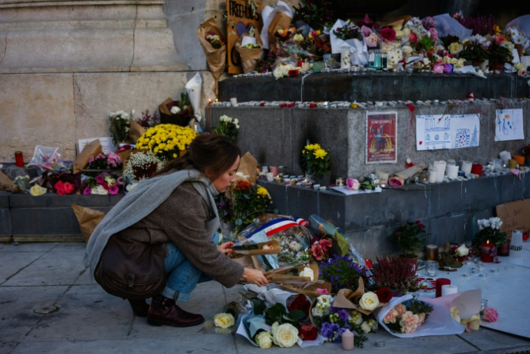 Une femme dépose des fleurs en hommage aux victimes du 13 novembre 2015, Place de la République à Paris, le 11 novembre 2025 ( AFP / Dimitar DILKOFF )