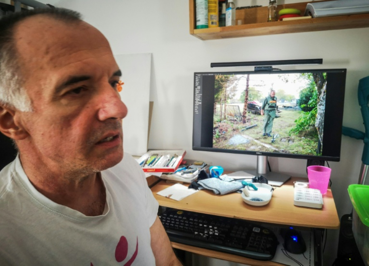Mirsad Tokic, ancien démineur qui a perdu une jambe dans une explosion en 2007, devant sa photo sur l'ordinateur en tenue de démineur, le 25 mars 2026 à Zagreb, en Croatie ( AFP / Tina SMOLE )