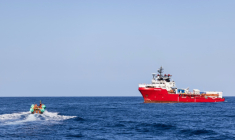 Le navire de sauvetage Ocean Viking en attente tandis qu'une embarcation pneumatique rigide transporte des migrants évacués d'un navire marchand, dans la zone de recherche et de sauvetage en eaux internationales au large des côtes libyennes, le 17 janvier 2026 ( AFP / Sameer Al-DOUMY )