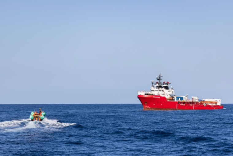 Le navire de sauvetage Ocean Viking en attente tandis qu'une embarcation pneumatique rigide transporte des migrants évacués d'un navire marchand, dans la zone de recherche et de sauvetage en eaux internationales au large des côtes libyennes, le 17 janvier 2026 ( AFP / Sameer Al-DOUMY )