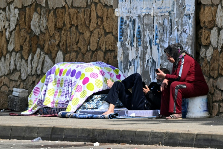 Des habitants déplacés ayant fui les frappes aériennes israéliennes dans la banlieue sud de Beyrouth assis le long de la corniche, dans la capitale libanaise, le 6 mars 2026 ( AFP / Joseph EID )