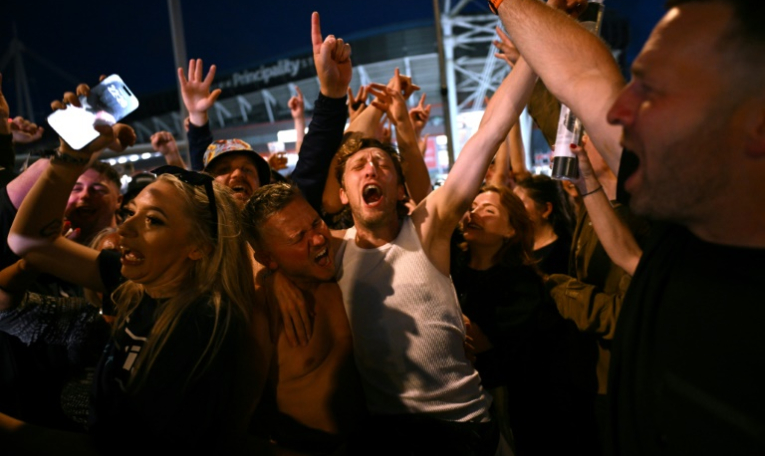 Les fans du groupe de rock britannique Oasis se réjouissent à l'extérieur du Principality Stadium à Cardiff le 4 juillet 2025 ( AFP / Oli SCARFF )
