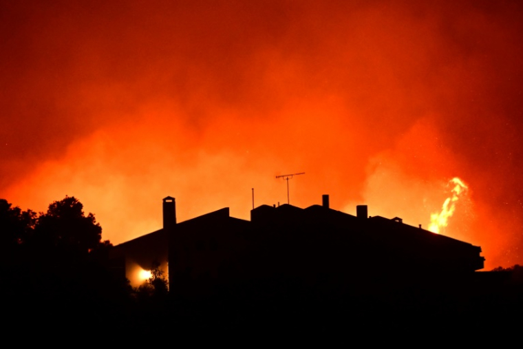 Les flammes envahissent les champs et les bois près d'une maison alors qu'un incendie fait rage près de Palaia Fokaia, à environ 43 km au sud d'Athènes, le 8 août 2025. ( AFP / Aris MESSINIS )