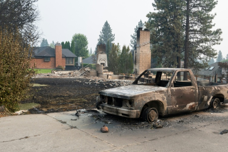 Une voiture calcinée devant les ruines d'une maison rasée par les flammes, à Spokane, dans l'Etat de Washington, le 2 août 2026 ( AFP / Erick DOXEY )