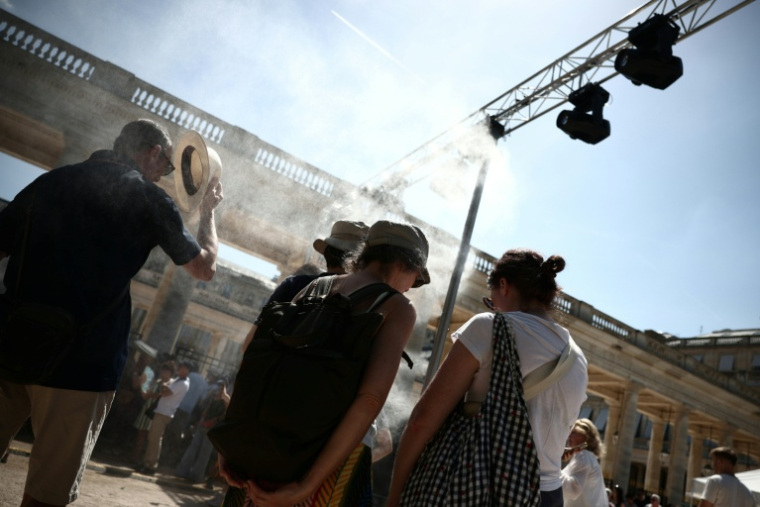 Des piétons se rafraîchissent sous un brumisateur installé par la mairie de Paris à l'occasion de la 45e édition de la Fête de la Musique à Paris, pendant un épisode de canicule en France, 21 juin 2026 ( AFP / Guillaume BAPTISTE )