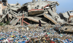 Une Palestinienne marche entre des détritus et un immeuble détruit, dans le camp de réfugiés de Nousseirat, dans le centre de la bande de Gaza, le 29 janvier 2026 ( AFP / EYAD BABA )