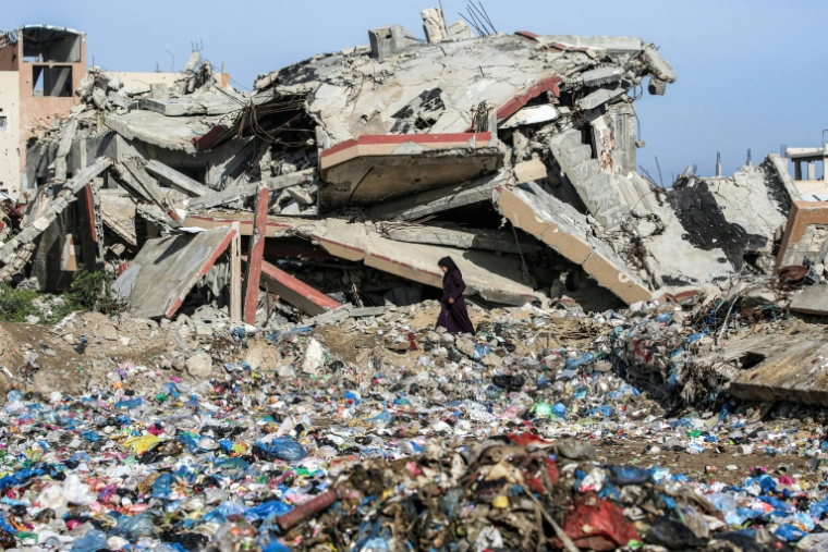 Une Palestinienne marche entre des détritus et un immeuble détruit, dans le camp de réfugiés de Nousseirat, dans le centre de la bande de Gaza, le 29 janvier 2026 ( AFP / EYAD BABA )