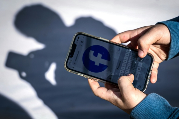 Un adolescent consulte Facebook sur son téléphone portable à Gosford, le 24 octobre 2025 en Australie ( AFP / David GRAY )