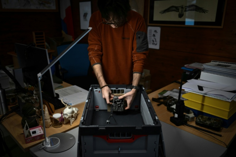 Marco Granata prépare un piège photographique utilisé pour surveiller les petits mustélidés, tels que les hermines, dans leur habitat naturel, à Entracque, dans le nord-ouest de l’Italie, le 22 décembre 2025 ( AFP / MARCO BERTORELLO )