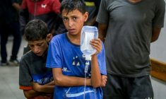 Un jeune palestinien tient une perfusion pour un homme blessé à l'hôpital Nasser, à Khan Younès, dans le sud de la bande de Gaza, le 20 juillet 2025 ( AFP / - )